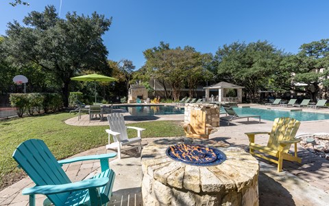 Outdoor fireplace with adirondack chairs | Austin apartment community